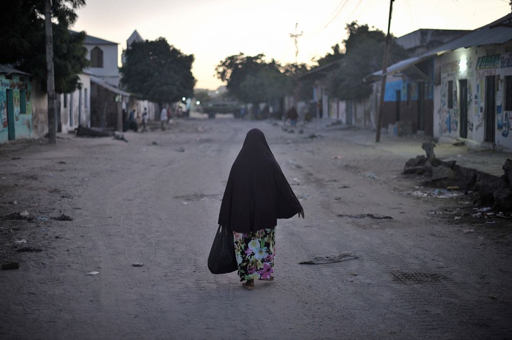 A woman walks down the street just after sunrise in Somalia's capital, Mogadishu. Original public domain image from Flickr