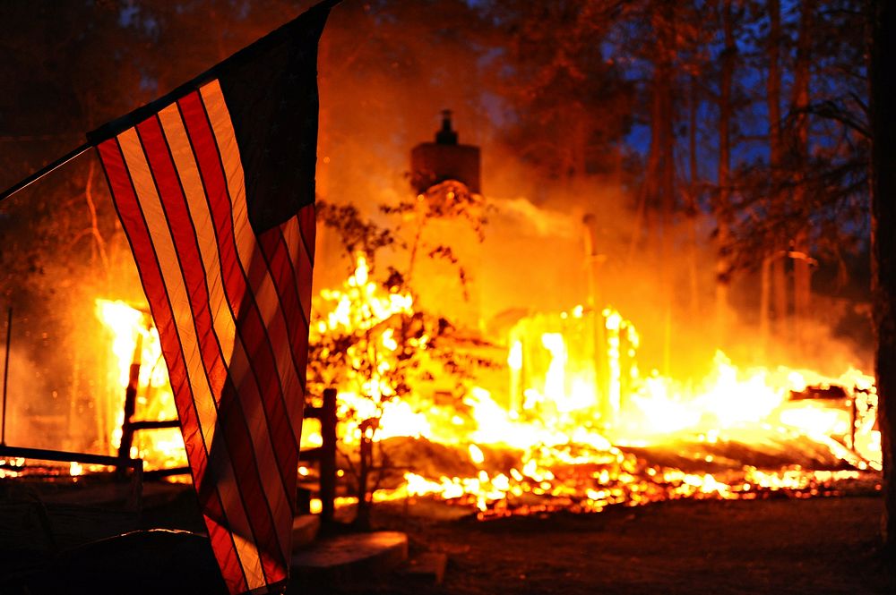 A U.S. flag hangs in front of a burning structure in Black Forest, Colo., June 12, 2013.