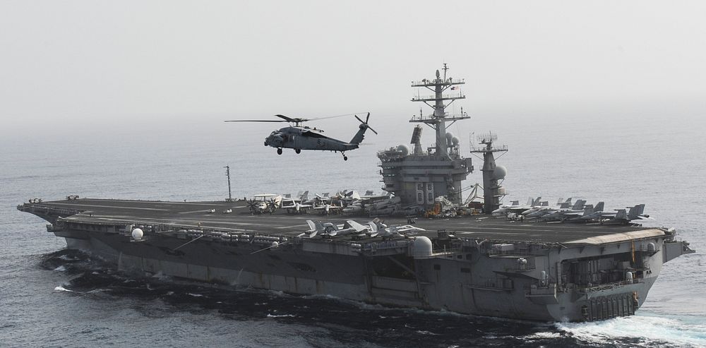 A U.S. Navy MH-60S Seahawk helicopter assigned to Helicopter Sea Combat Squadron (HSC) 6 flies by the aircraft carrier USS…