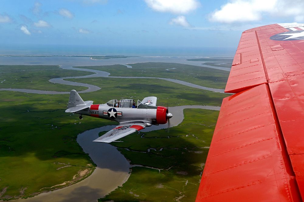 A retired U.S. Navy T-6 Texan trainer aircraft, left, flies beside a retired Navy C-45 Expeditor during the Salute from the…
