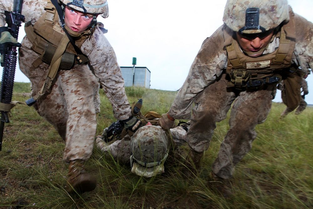 U.S. Marine Corps Lance Cpl. Rob Magnuson, left, and Lance Cpl. Rafael Cortez, right, drag Lance Cpl. Jeff Landis, a…