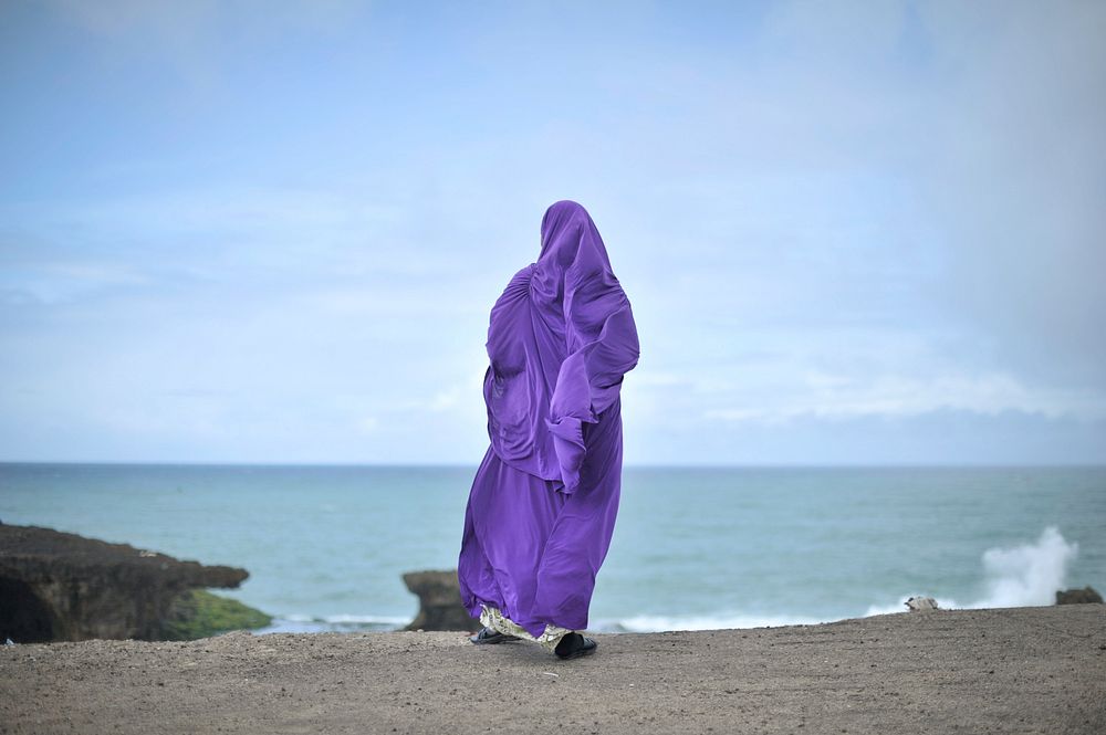 A woman stands in front of the ocean near Mogadishu's fish market, Somalia. Original public domain image from Flickr