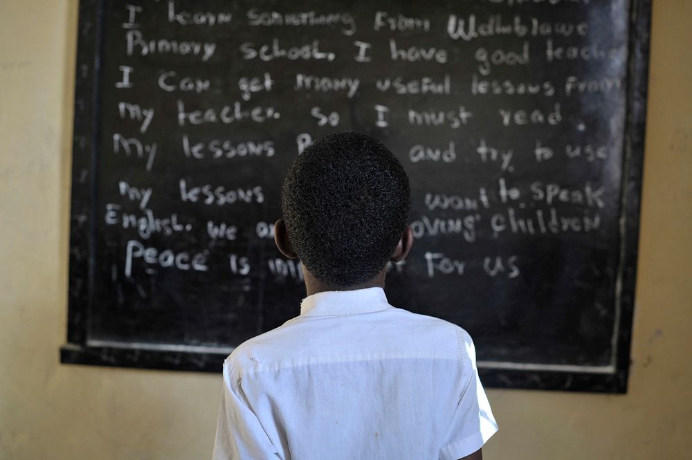 A Somali boy reads from the board during English class. Original public domain image from Flickr
