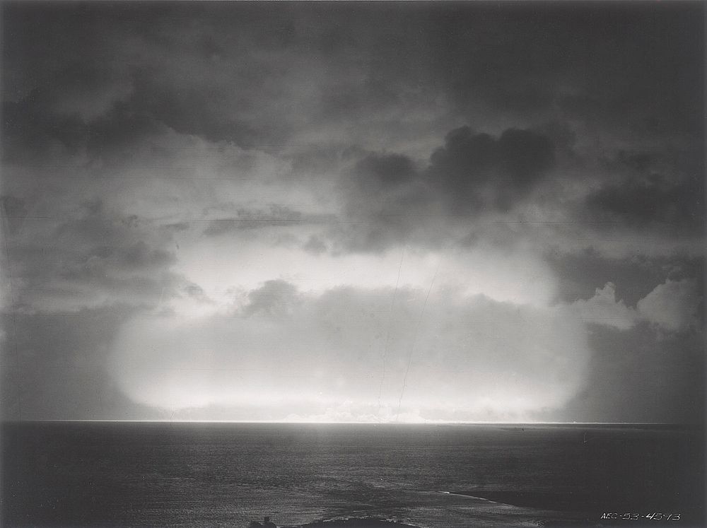 A nuclear detonation during the 1951 spring tests at Eniwetok Atoll is shown with smoke trails from rockets designed to…