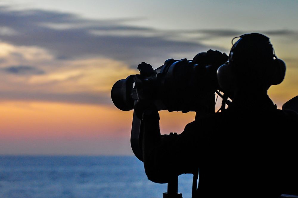 U.S. Navy Seaman Villard Vitalis, assigned to the amphibious assault ship USS Boxer (LHD 4), uses the ship?s binoculars to…