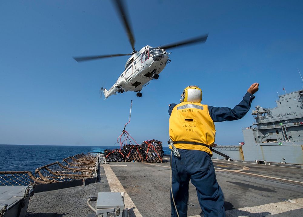 U.S. Navy Boatswain's Mate 3rd Class Shane Hempfield directs a Military Sealift Command SA-330J Puma helicopter delivering…