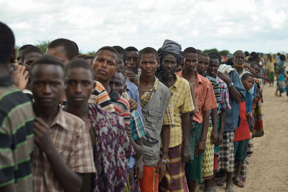 Internally Displaced People, affected by flooding and clan conflict, wait for a food handout at an AMISOM military camp near…