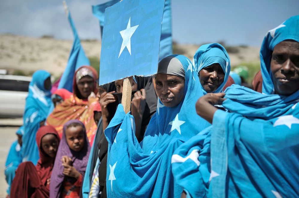 Somali women, wearing clothing with the Somali flag on it, dance and sing at a handover ceremony of a new well donated by…