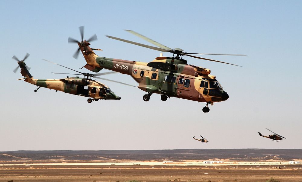 Royal Jordanian Air Force AS332 Super Puma and AH-1 Cobra helicopters fly away after dropping off special operations forces…