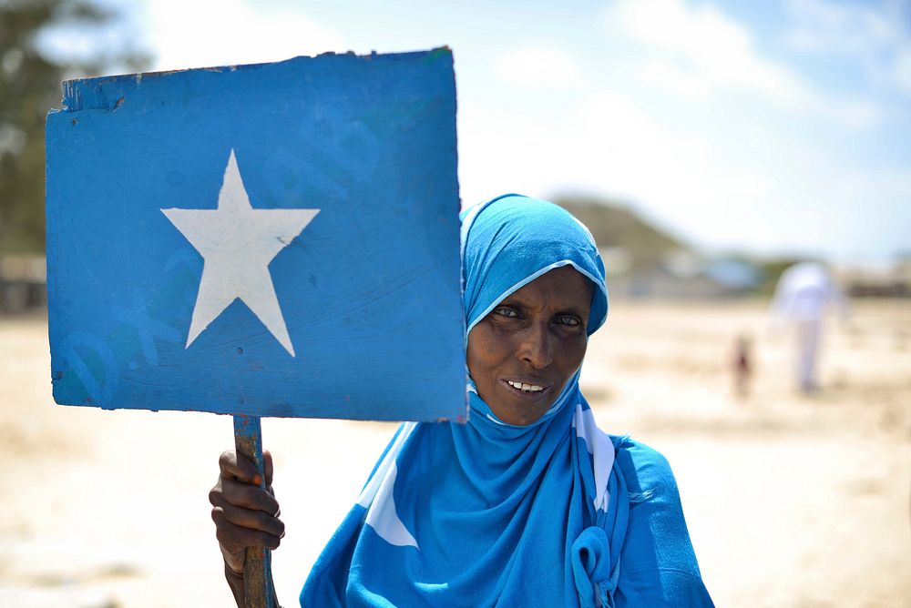A Somali woman, wearing clothing with the Somali flag on it, holds a placard at a handover ceremony for a new well donated…