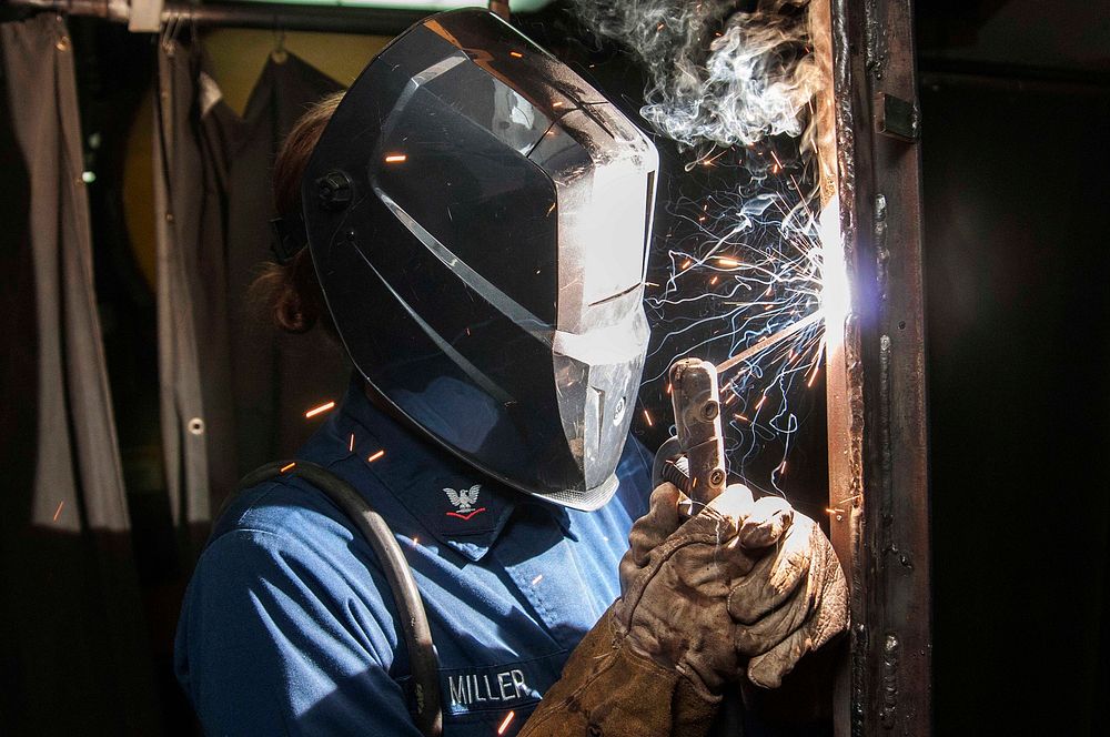 U.S. Navy Hull Maintenance Technician 3rd Class Hanna Miller practices vertical welding in the repair shop aboard the…