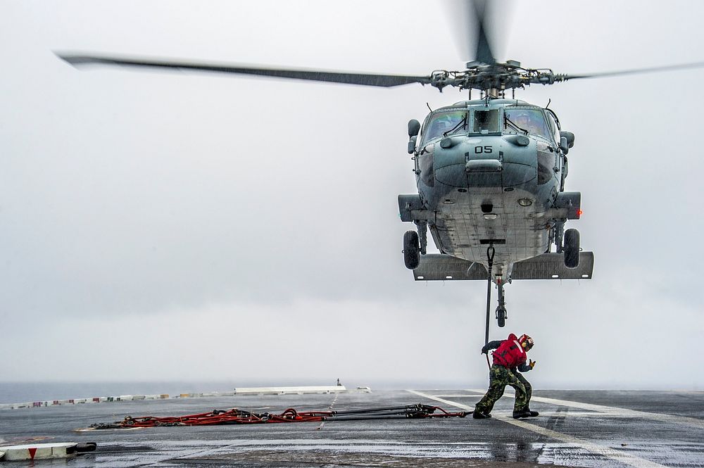 U.S. Sailors prepare to run to safety after attaching cargo legs to an MH-60S Seahawk helicopter attached to Helicopter Sea…