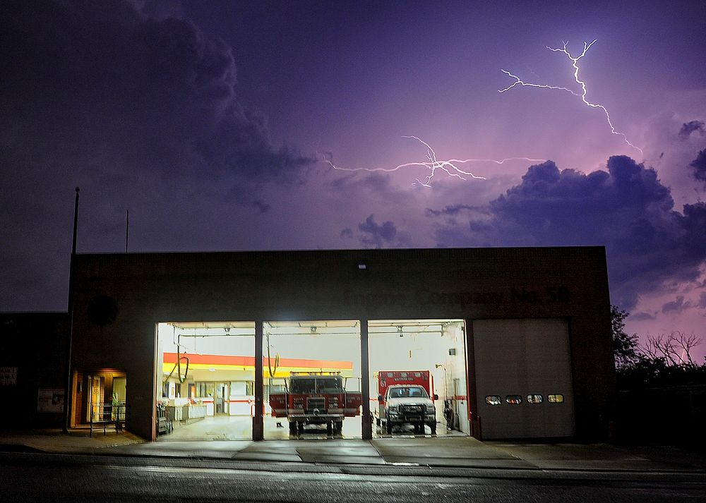 Lightning illuminates the sky outside of the fire department during a storm. Original public domain image from Flickr
