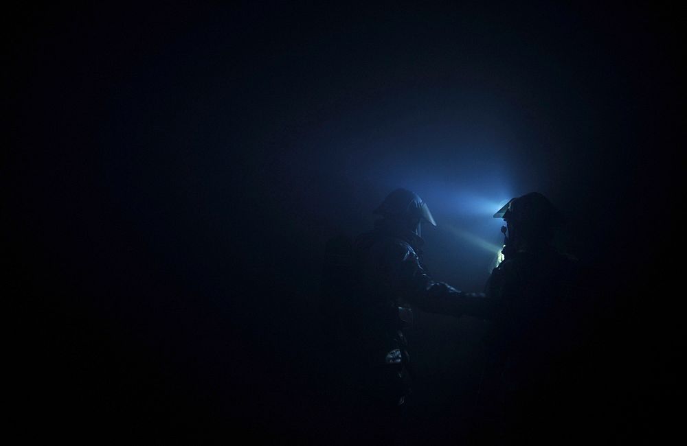 U.S. Air Force active duty and Air National Guard firefighters find their way through a simulated building fire during a…