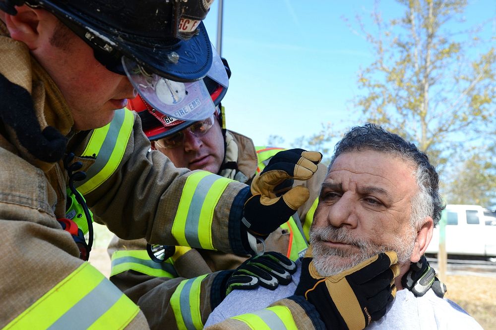 Firefighter checking the wellbeing of a simulated patient during a drill. Original public domain image from Flickr