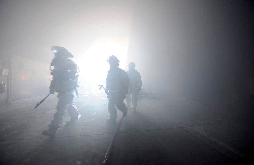 U.S. Air Force active duty and Air National Guard firefighters find their way through a simulated building fire during a…