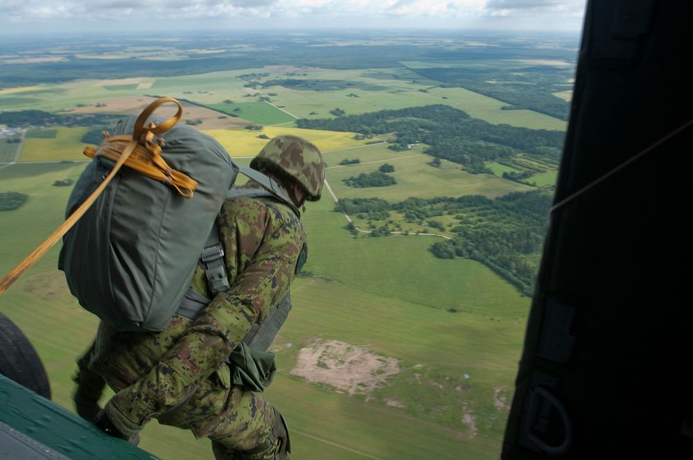 An Estonian paratrooper makes his leap out of an American UH-60 Black Hawk helicopter July 23, onto a drop zone in Nurmsi…