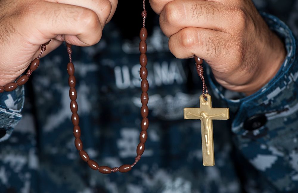 U.S. Navy MC2 Ruben Reed, a mass communications specialist with the American Forces Network (AFN) in Europe, holds a rosary…