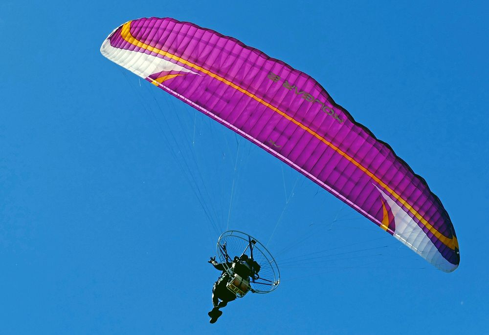 Powered paragliding with blue sky background. Original public domain image from Flickr