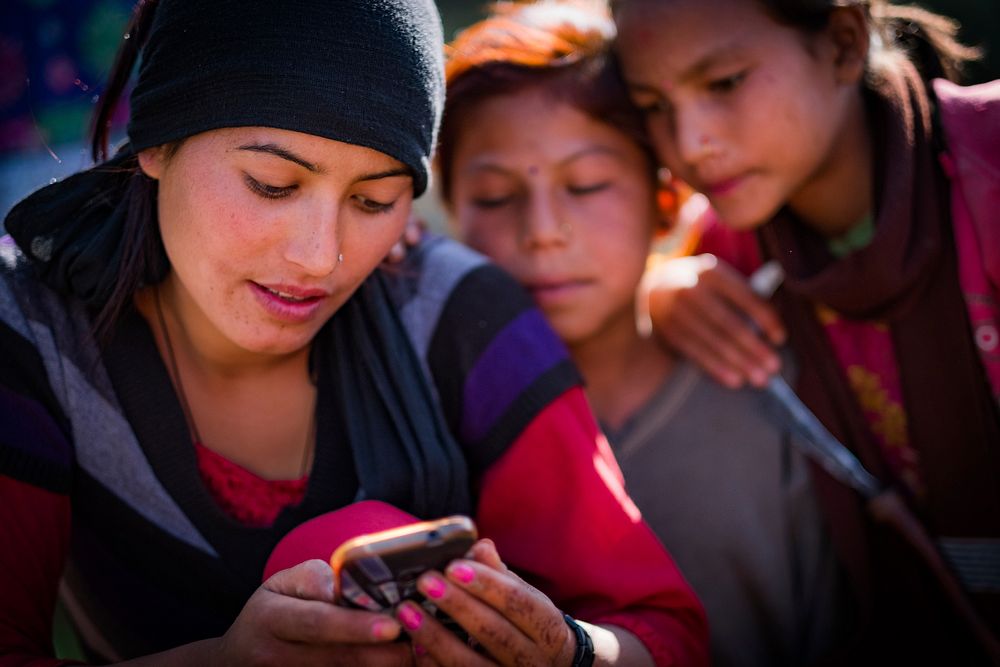 Woman and children looking at phone, Kailah, Bajhang District, Nepal, October 2017.