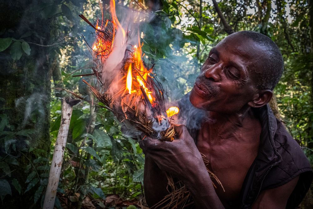 African man blowing on fire, Buhoma, Uganda, September 2017.