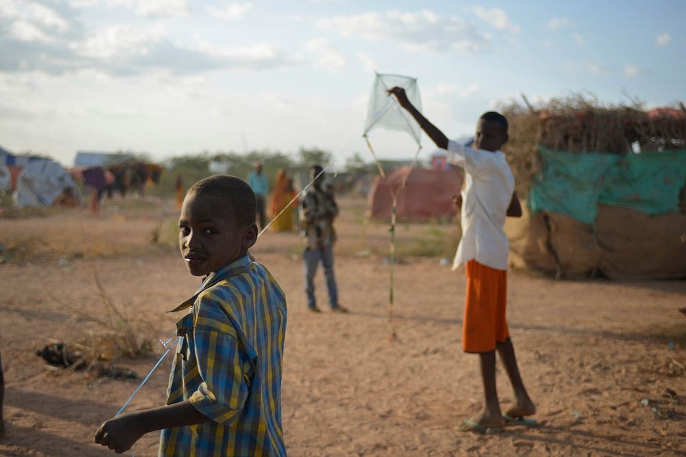 A boy flys his homemade kite at an IDP camp near the town of Beletweyne, Somalia, on May 28, 2016. Original public domain…