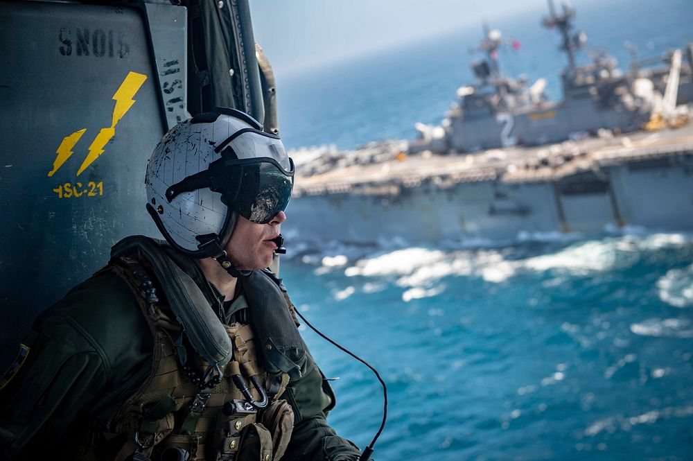U.S. Navy Aircrewman (Helicopter) 2nd Class Eric Smith rides in an MH-60S Seahawk helicopter, attached to the…