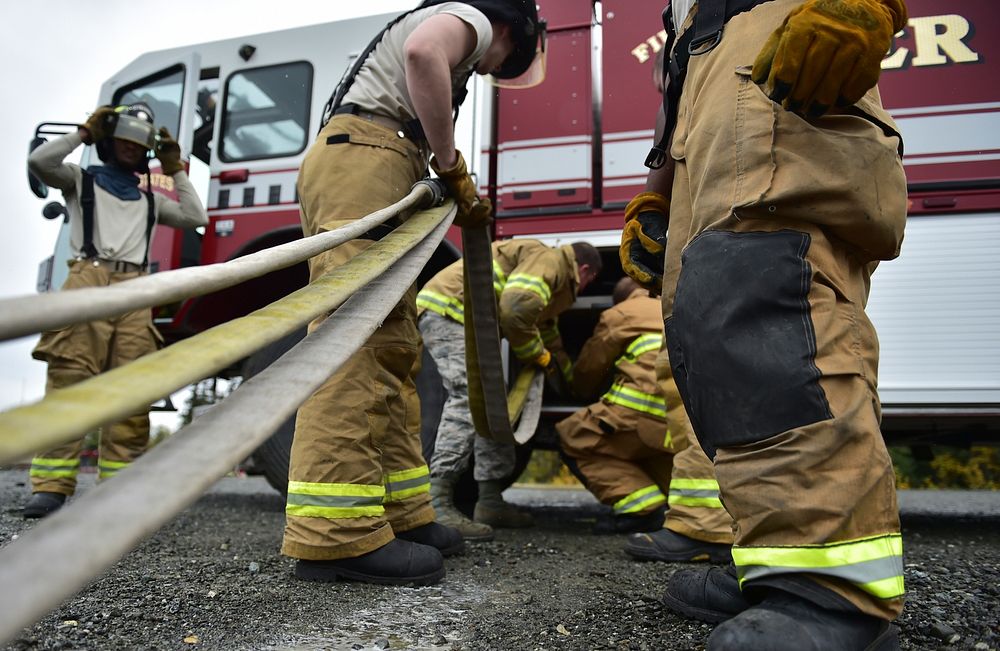Fire protection specialist Airmen assigned to the 673rd Civil Engineer Squadron roll up water hoses after firefighter…
