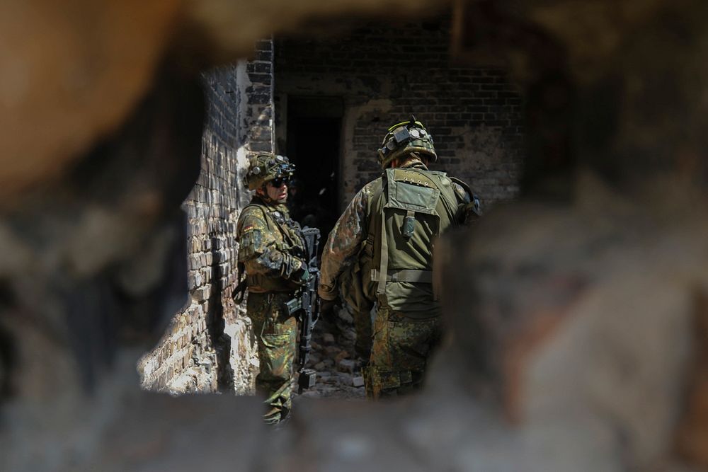 German army infantrymen with the 391st Mechanized Infantry Battalion plan their next maneuver in a recently secured building…