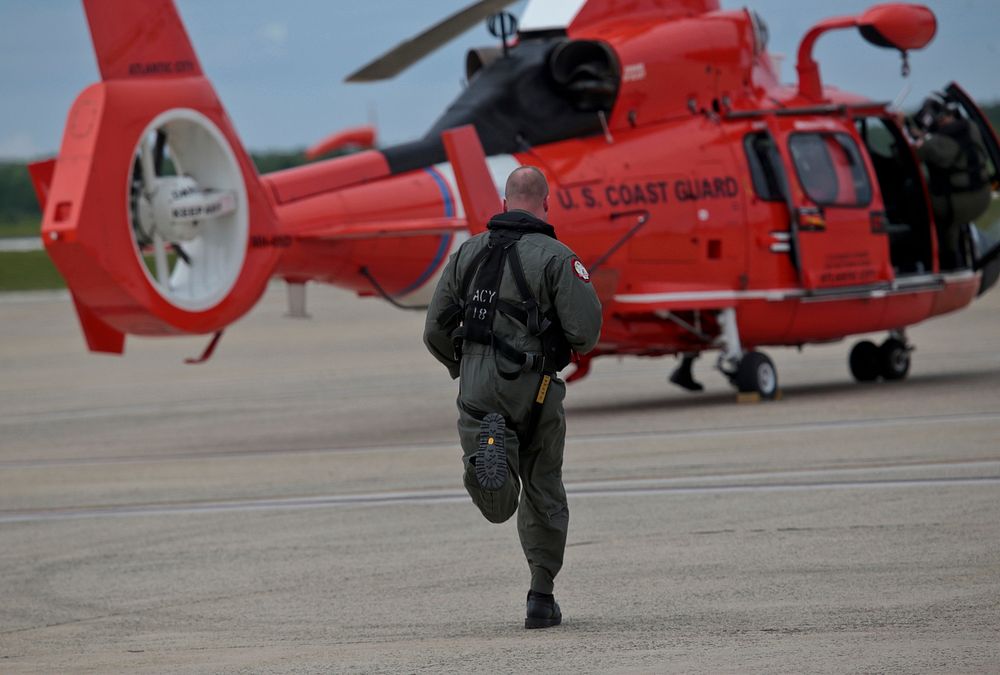A U.S. Coast Guard HH-65C Dolphin crew member from Coast Guard Air Station Atlantic City runs to his helicopter after an…