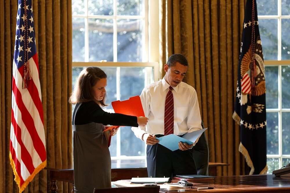 President Barack Obama looks at daily correspondence with his personal secretary Katie Johnson in the Oval Office, Jan. 30…