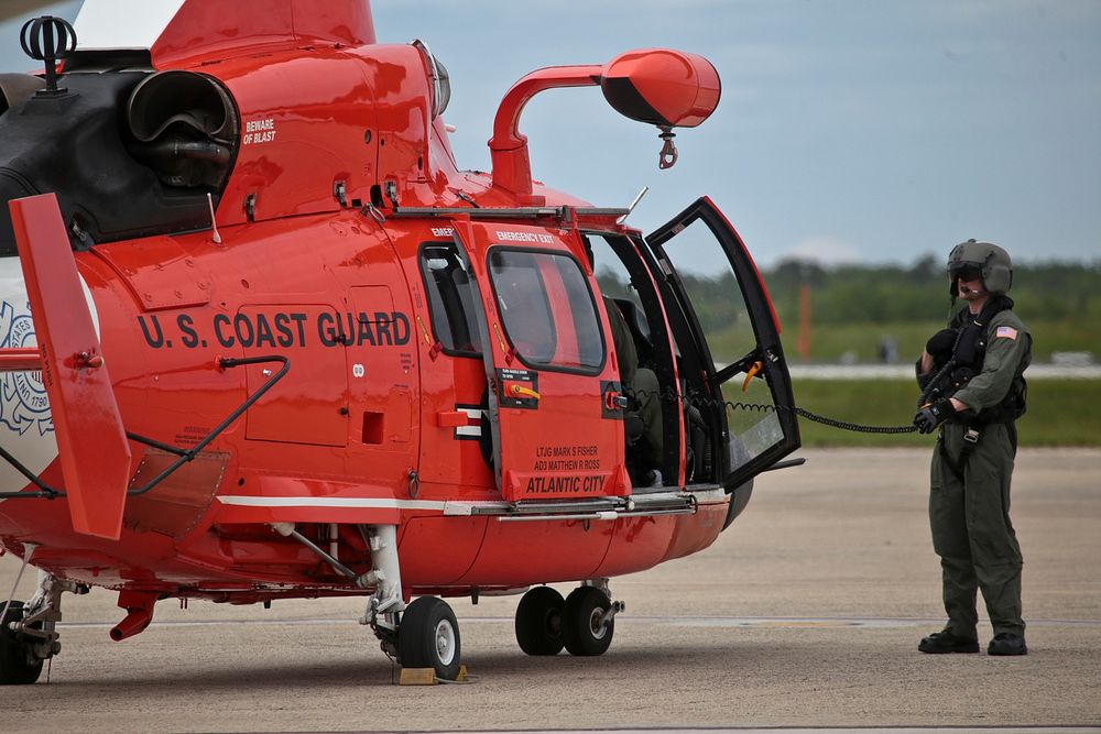 A U.S. Coast Guard HH-65C Dolphin crew chief from Coast Guard Air Station Atlantic City preps the aircraft for takeoff after…