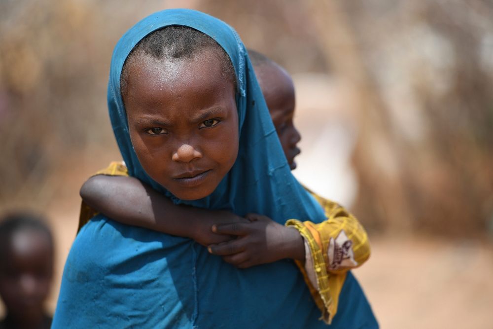 A girl carries her brother at an Internally Displaced Persons camp in Doolow, Gedo region, Somalia on June 12, 2017. A…