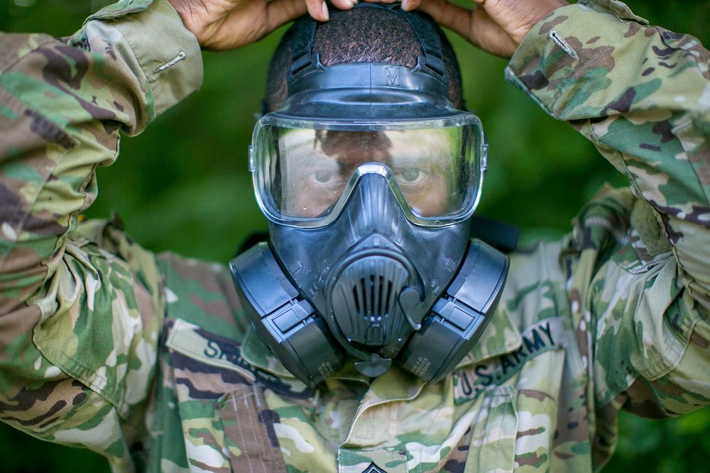 U.S. Army Sgt. 1st Class Joaquin Spikes, assigned to the U.S. Army Security Assistance Command, securely straps his gas mask…