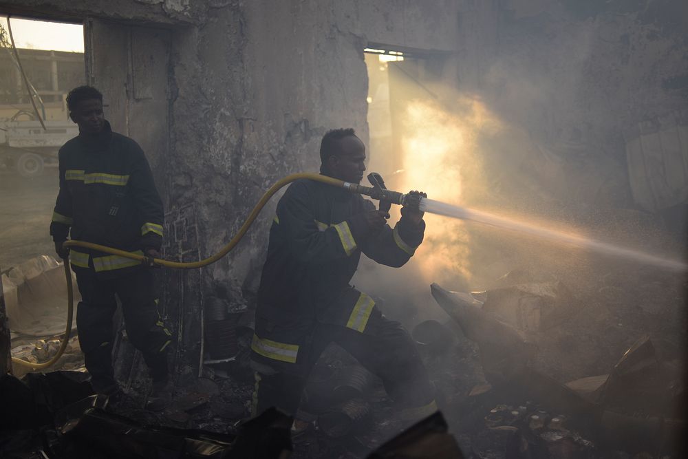 A fireman sprays water at a fire still burning at the site of a VBIED attack undertaken by the militant group al Shabaab in…