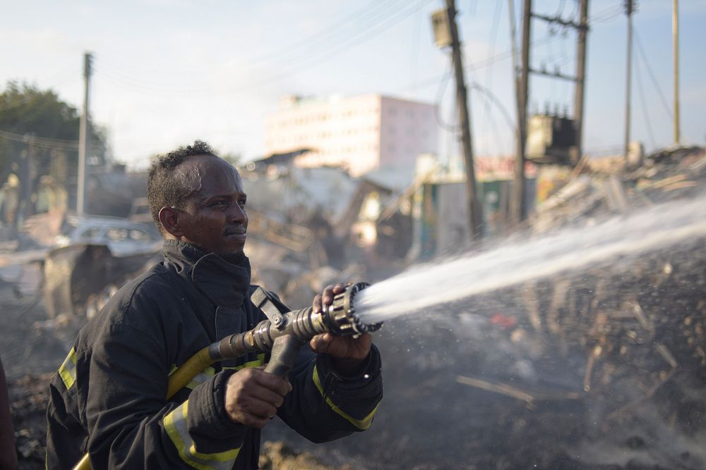 A fireman sprays water at a fire still burning at the site of a VBIED attack undertaken by the militant group al Shabaab in…