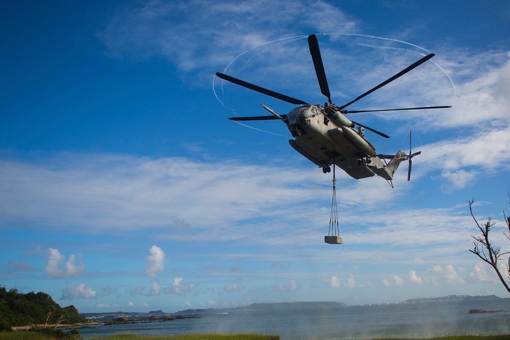 A U.S. Marine Corps CH-53E Super Stallion hovers over a landing zone with a cement block during an external lift drill with…