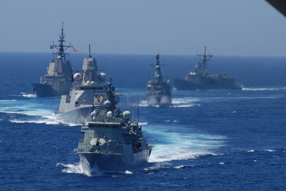 Five NATO ships prepare for a pass and review during the North Atlantic Council and Military Committee Sea Day off the coast…