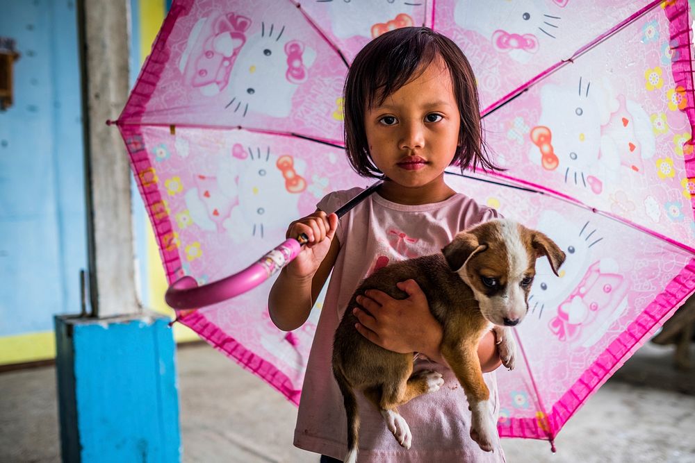 Little girl holding puppy, Nueva Vizcaya, Philippines, July 2017.