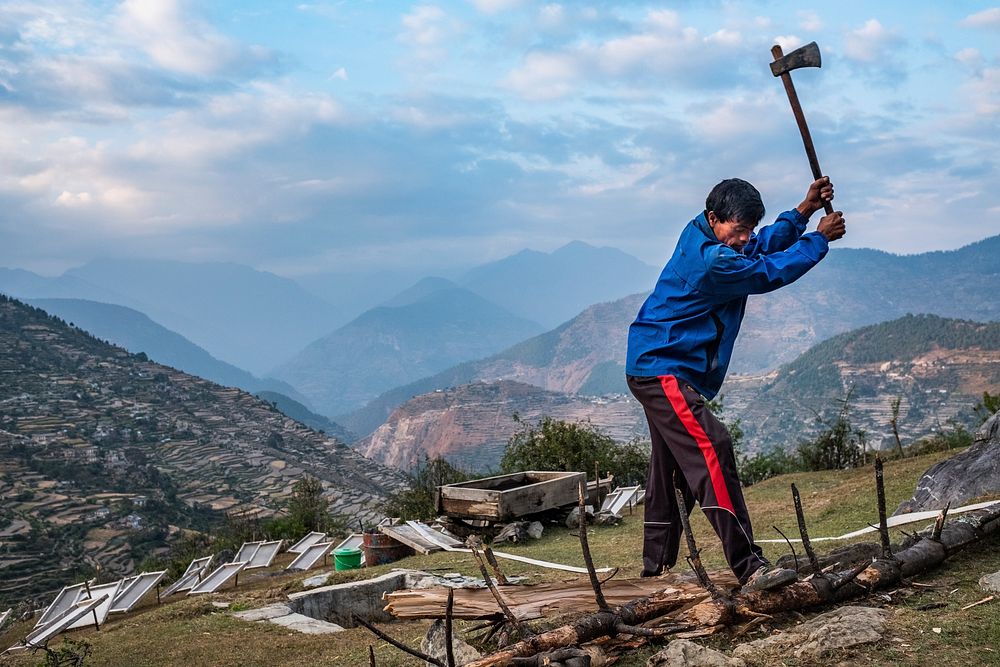 Man using axe, cutting wood, Kailash, Bajhang District, Nepal, October 2017.