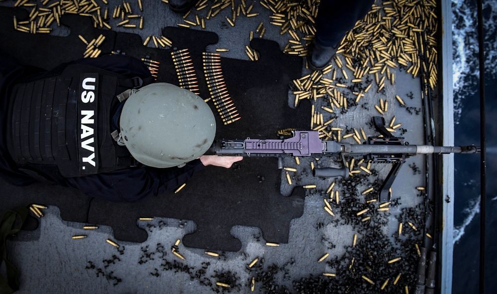 U.S. Navy Damage Controlman Fireman Brian Botez fires an M240B machine gun during a weapons qualification course aboard the…