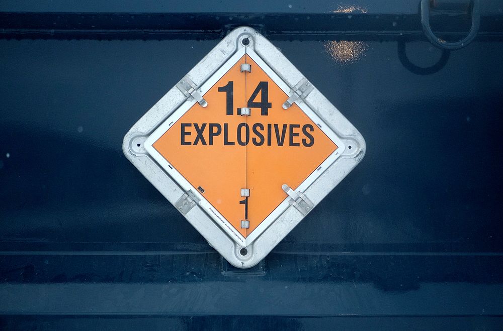 An explosives sign is seen on the side of a vehicle transporting ammunition for Airmen. Original public domain image from…