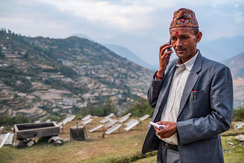 Man in kufi cap on phone, Kailash, Bajhang District, Nepal. October 2017.