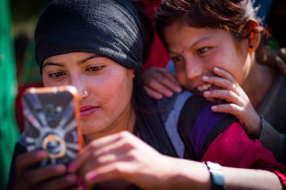 Woman and girl using phone in Kailash, Bajhang District, Nepal, October 2017.