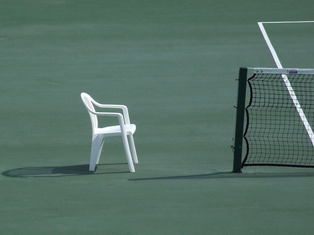 Empty tennis court with chair. Free public domain CC0 photo.