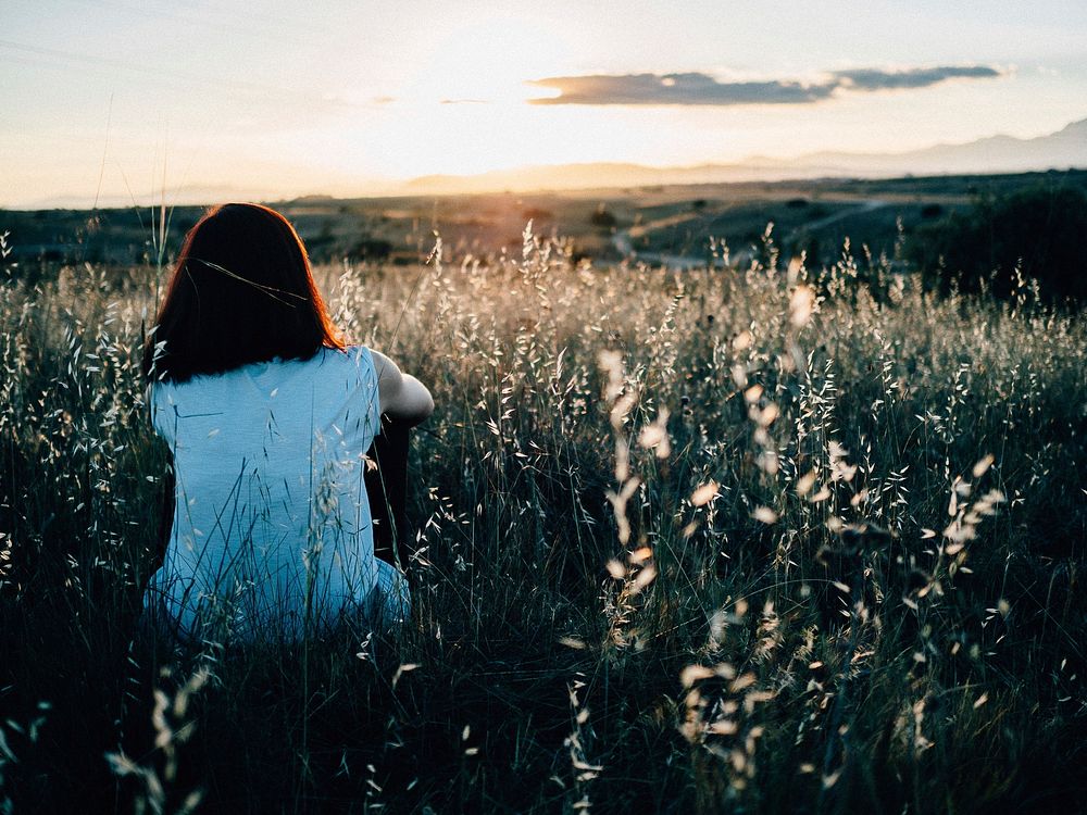 Girl sitting in the meadow during sunset, free public domain CC0 photo.