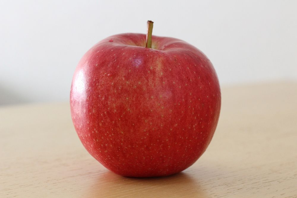 Closeup on red apple on wooden table. Free public domain CC0 photo.