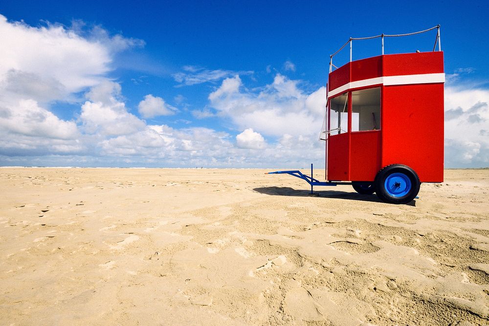 Red kiosk with wheel on the beach. Free public domain CC0 photo.