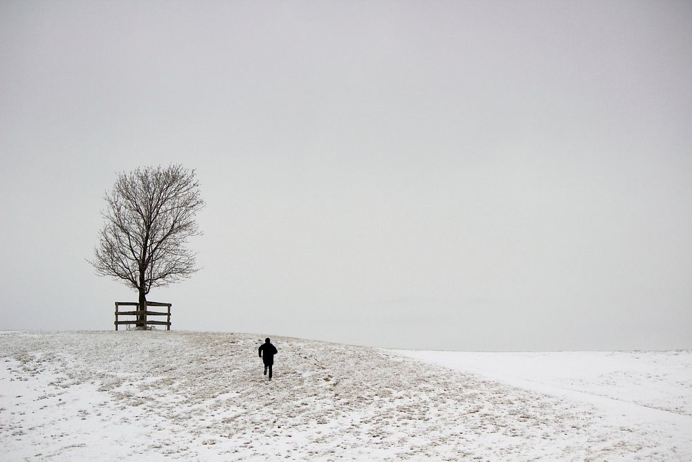 A running figure and a tree on a snowy hill with foggy background