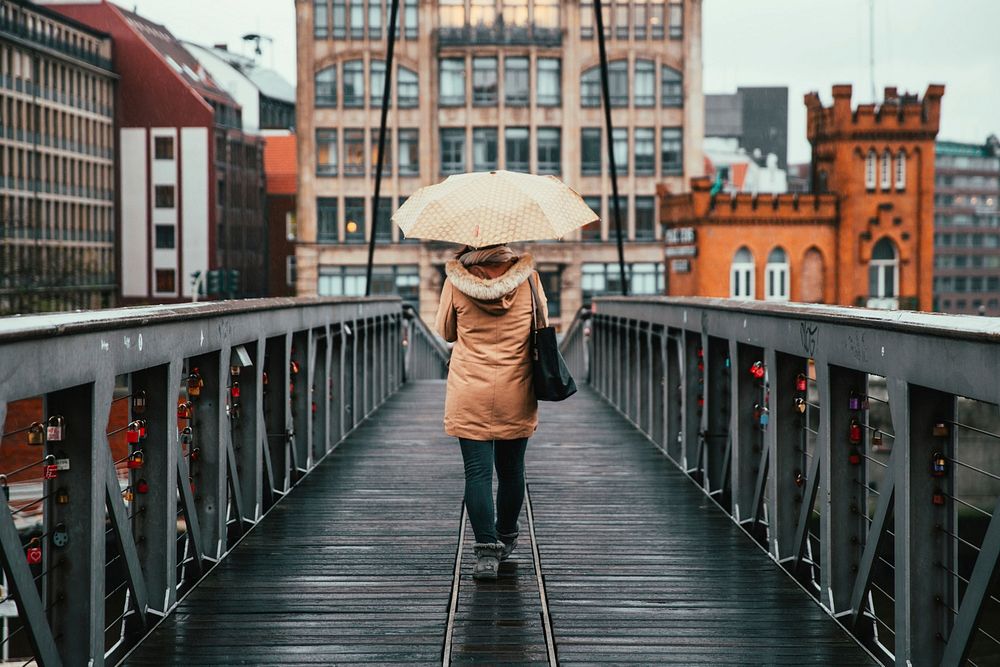 A woman holding umbrella walking on the bridge on a rainy day